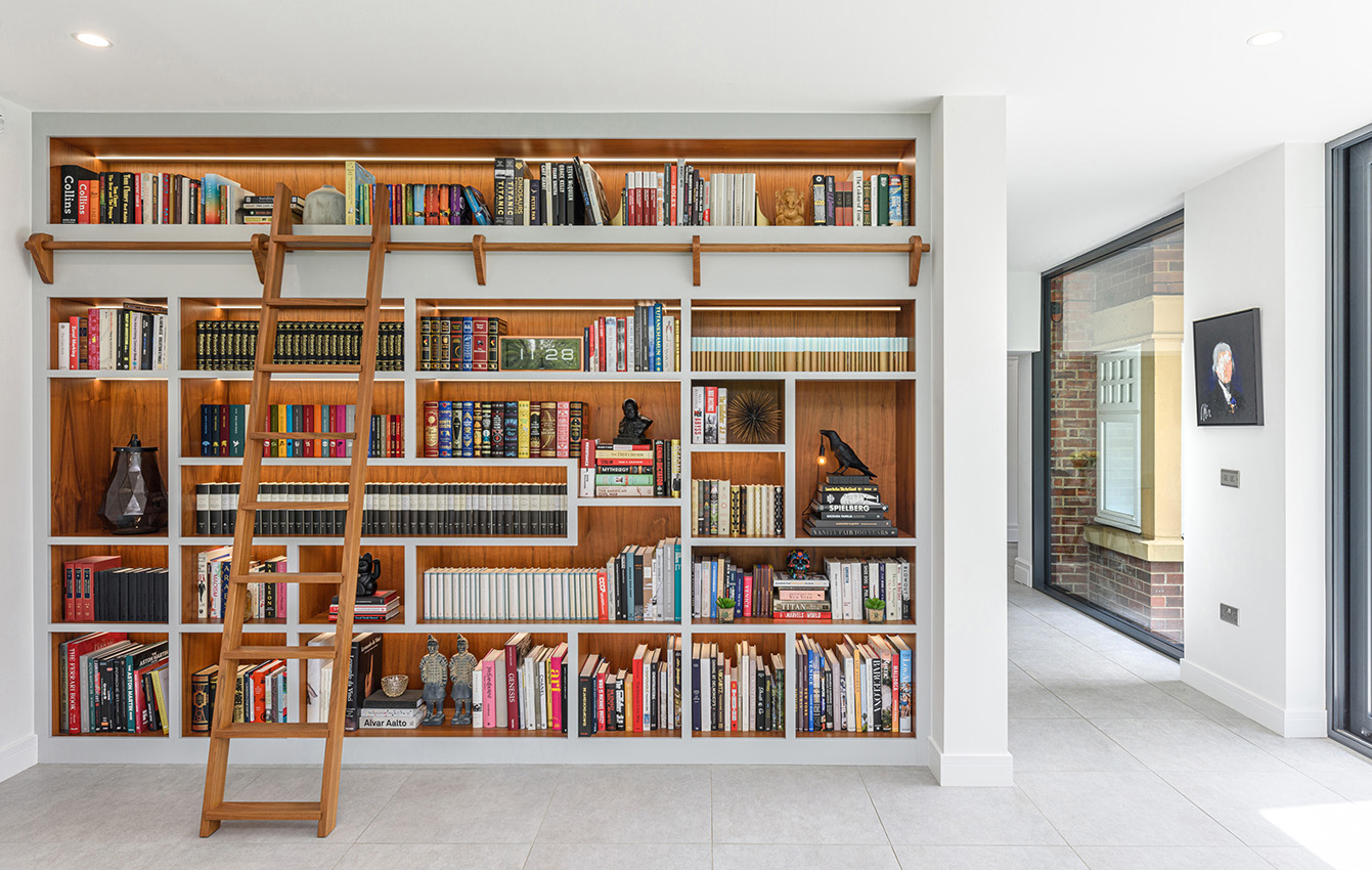 A detail of an interior showing a bookcase with a ladder for access