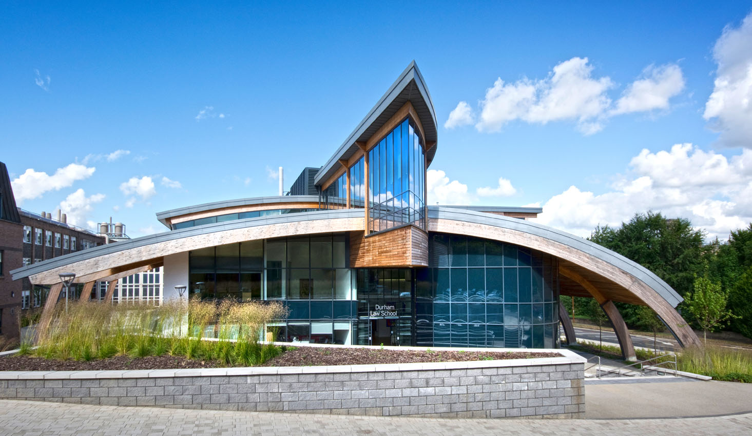 Architectural exterior of a partial wooden clad building taken in summer from street level