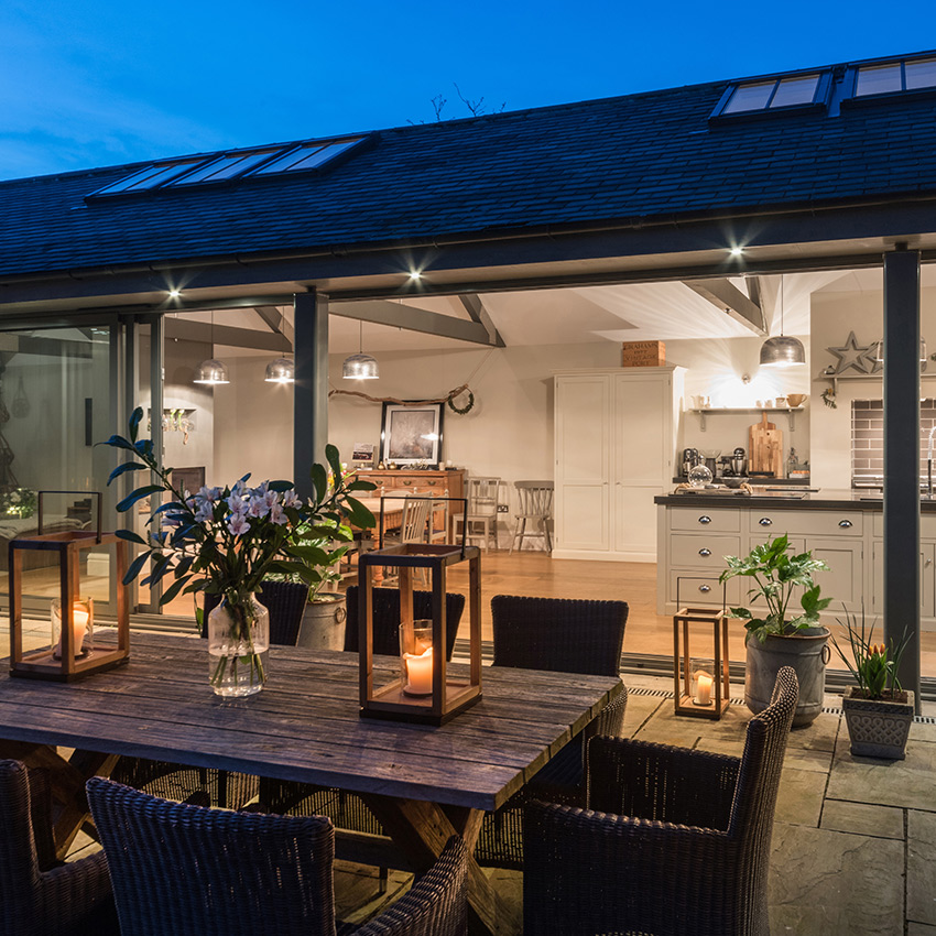 Exterior detail looking into an illuminated kitchen area at dusk