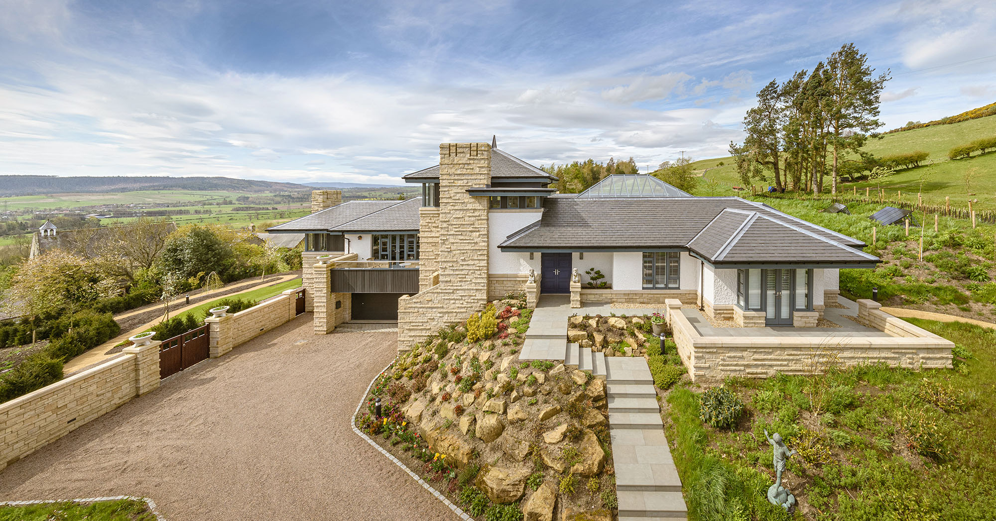 Elevated exterior or a residential property with steps and rockery in the forground and views over the countryside