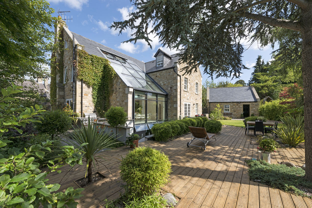 Residential exterior of a property with decking and outdoor entertaining area in summer