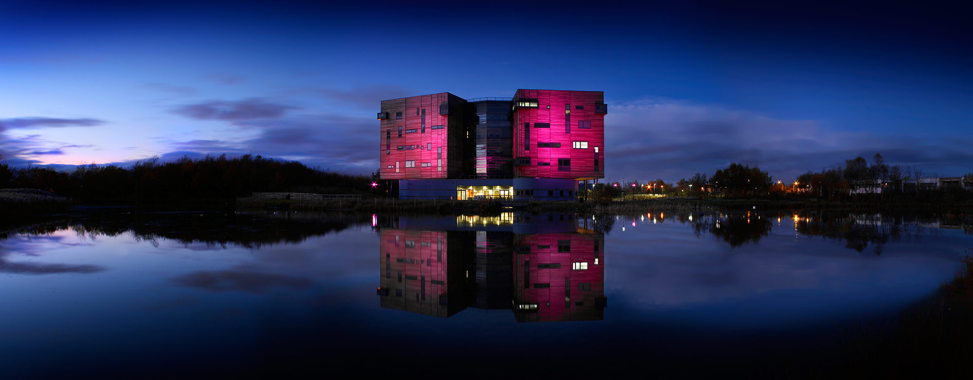 Quadrus Centre wooden clad office buidling at dusk with reflections of the building in lake