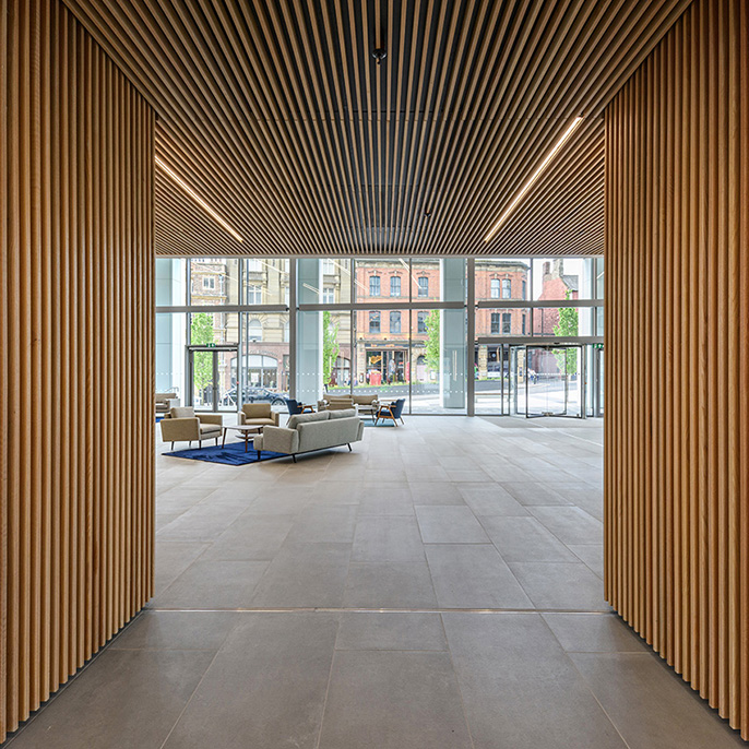 Interior of a commercial office building with wooden design features looking towards a glazed area at dusk