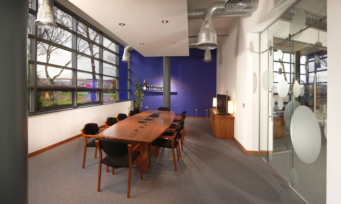 Commercial office meeting room with feature wall and exposed ducting with suspended ceiling