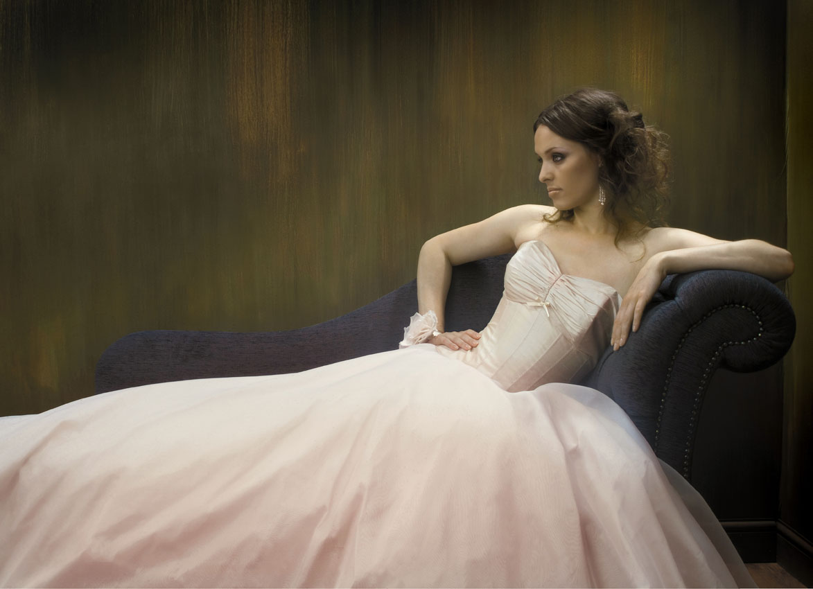Model wearing a bridal dress against a golden green backdrop