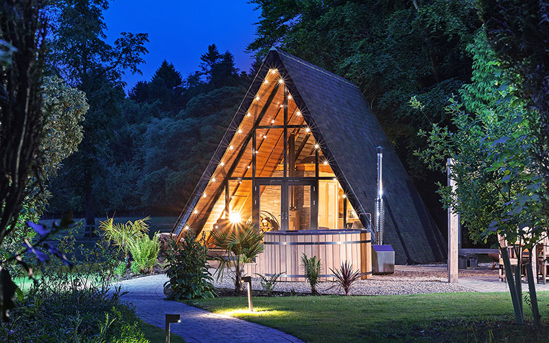 A-Frame garden building illuminated at dusk in a garden setting