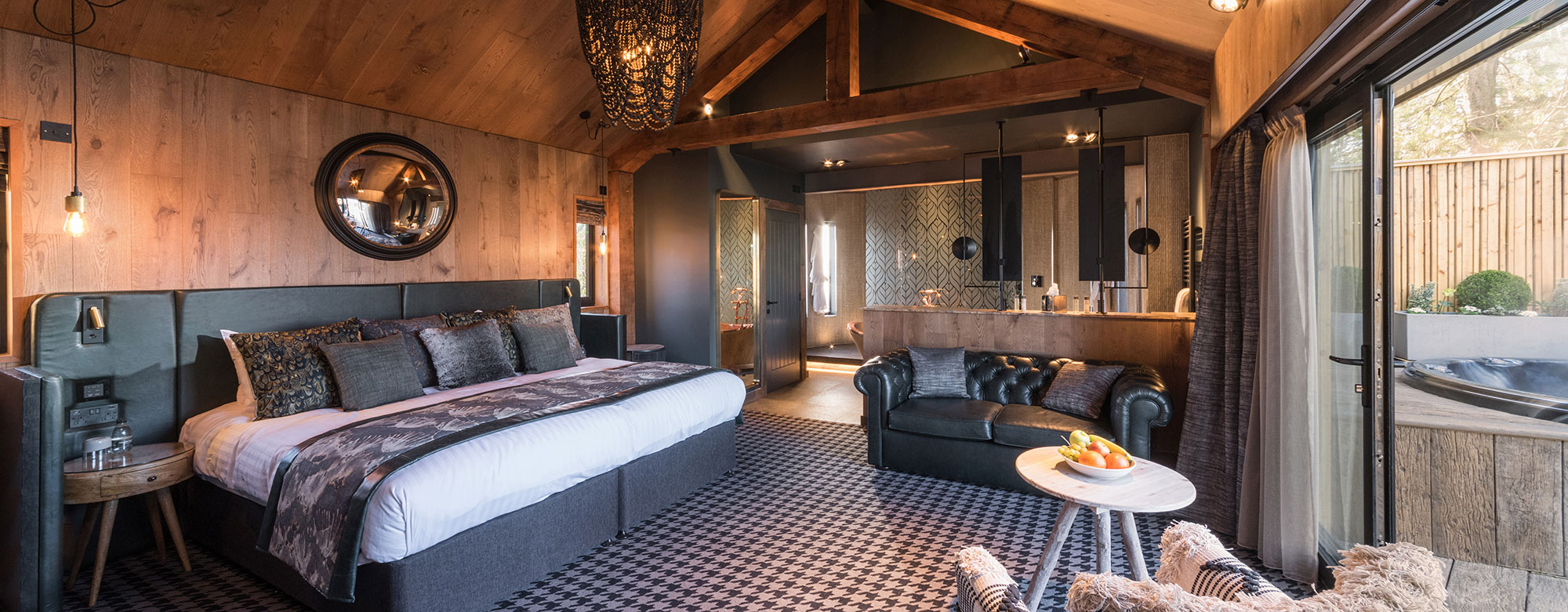 Interior of a bedroom in a treehouse with open plan bathroom and view to hot tub