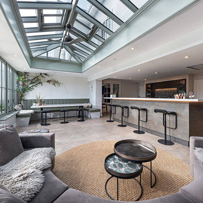 Interior of an orangery looking over furniture towards an open plan kitchen