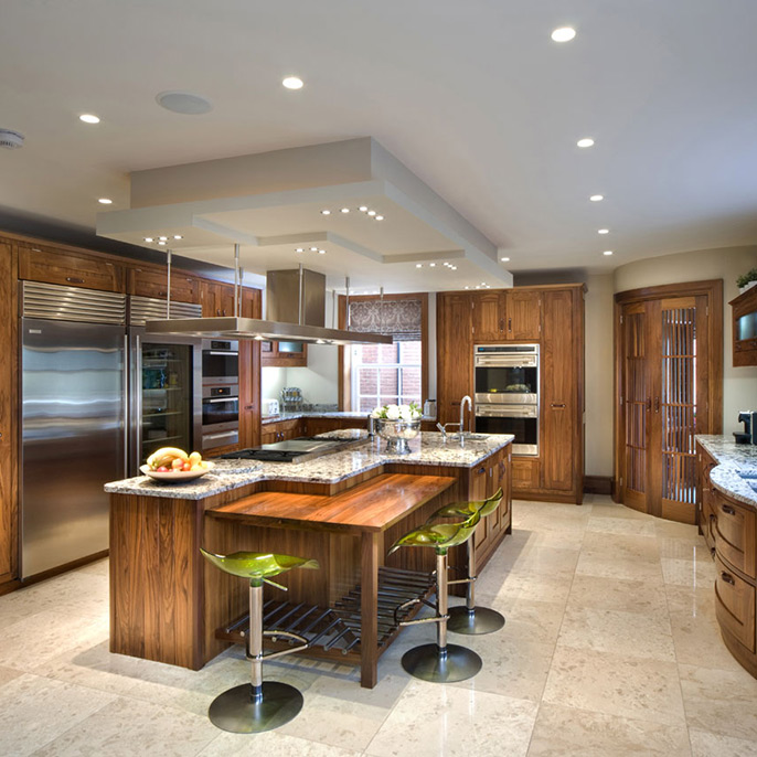 A interior view of a wooden fitted kitchen with island area, feature lighting and furniture
