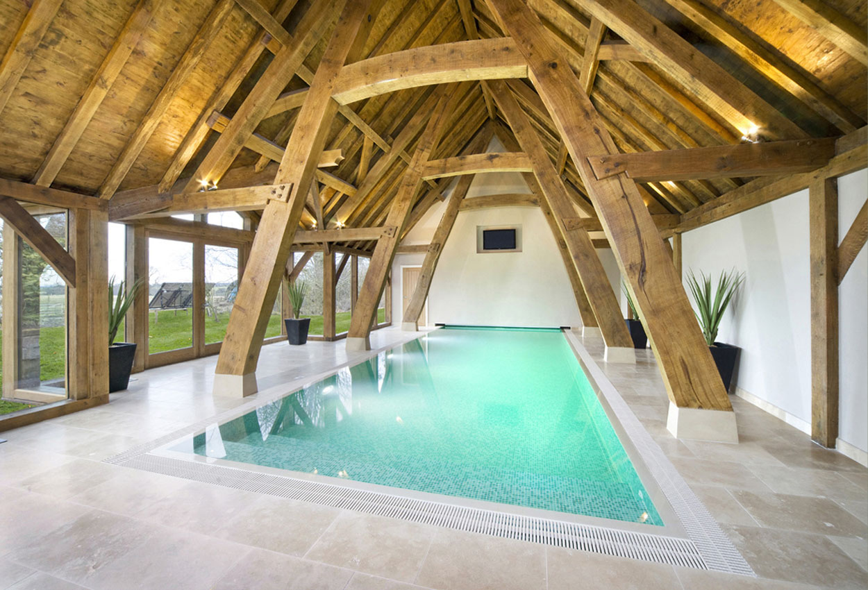 A residential swimming pool with old wooden beams and views over the countryside