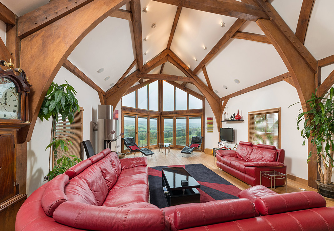 Residential property interior with high exposed roof beams and large window overlooking the countryside